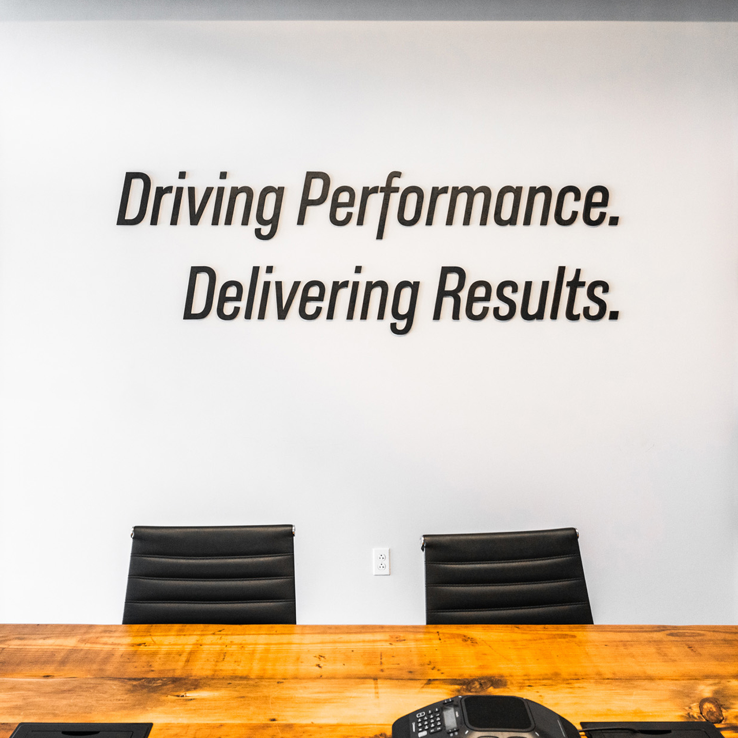 Office with the words, "Driving Performance. Delivering Results" on the wall